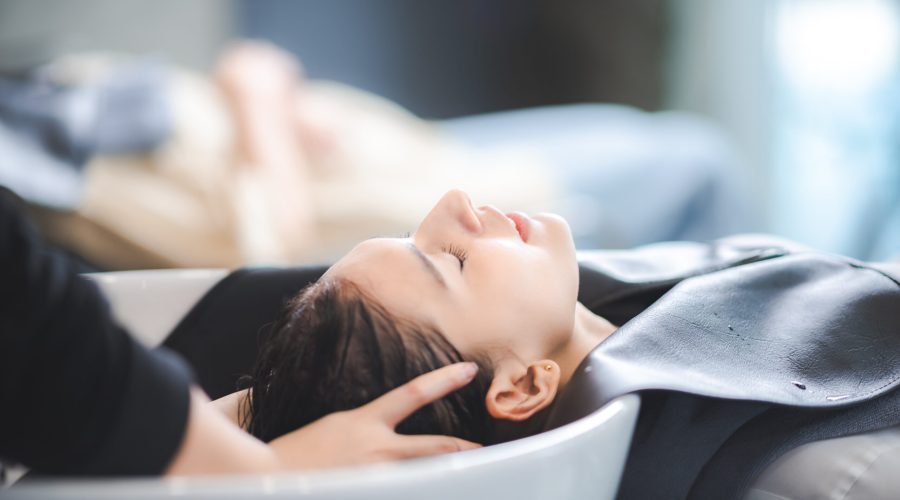 professional hairdresser woman are washing client hair in beauty salon, female head treatment and health care concept, person clean a hair by using water and shampoo to fashion hair care coiffure
